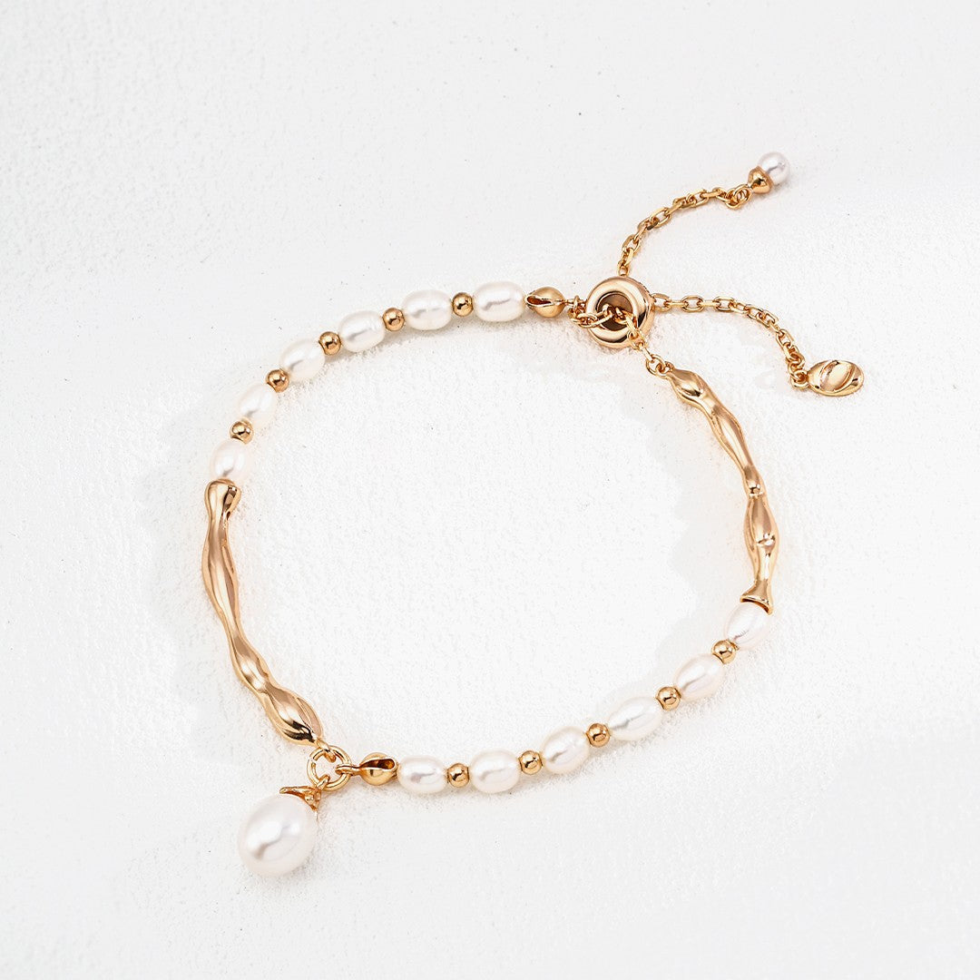 Close-up of wrist with two gold bracelets, one with tiger's eye gemstones, elegant jewelry from Chanqinfang