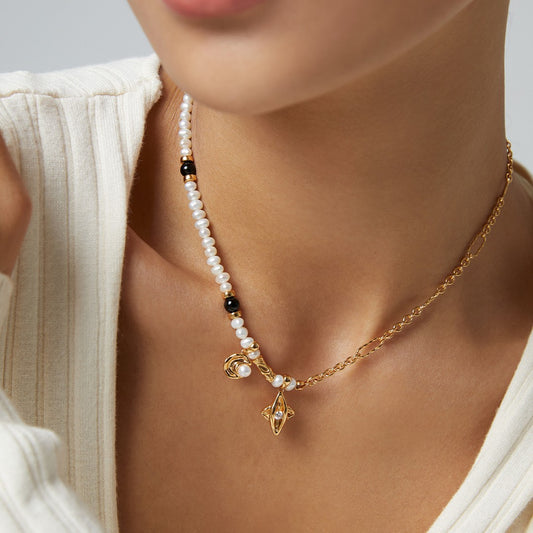 Close-up of woman's neck wearing a unique gold necklace with pearls, black beads, and two gold charms