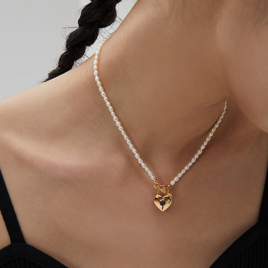 Close-up of woman wearing a pearl necklace with a gold heart-shaped lock pendant