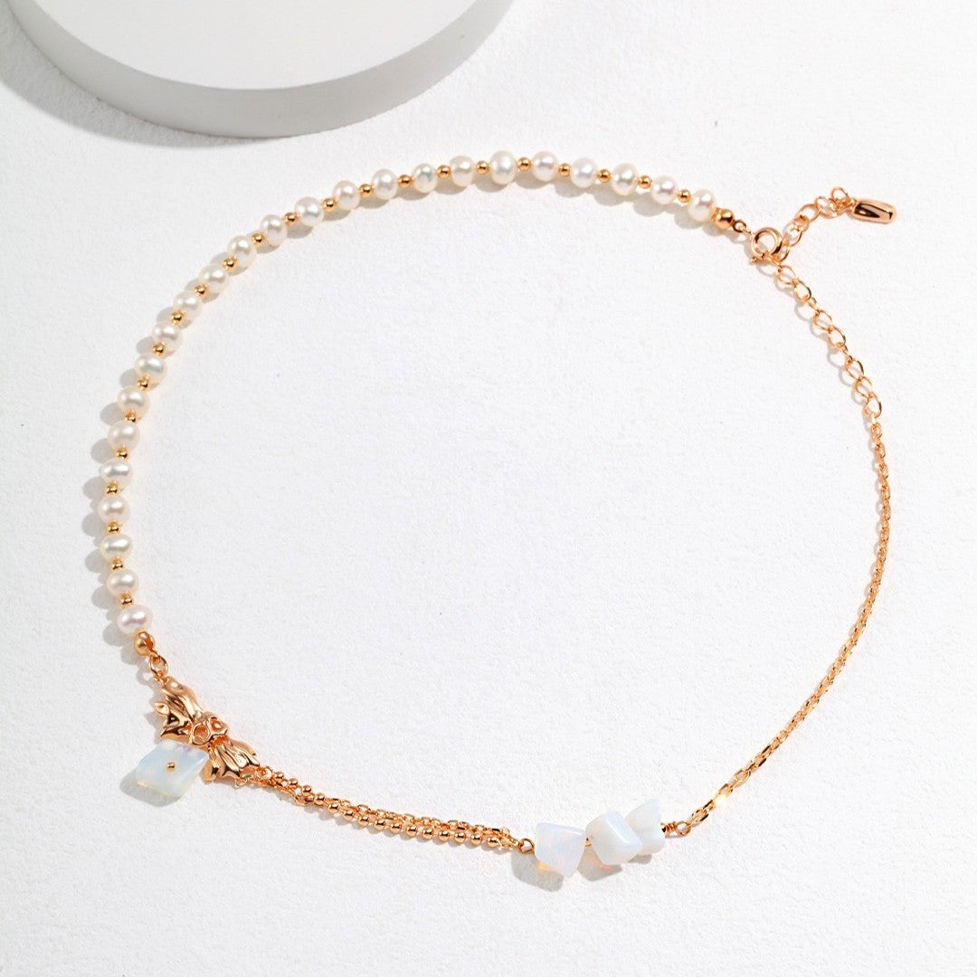 Delicate gold and pearl choker necklace with opal stone accents on white background