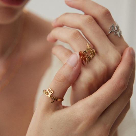Close-up of hands wearing personalized gold and silver name rings Skye and Gerald Walker