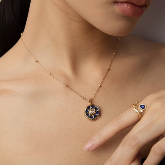 Close-up of woman wearing gold necklace with blue star pendant and gold ring with blue stone