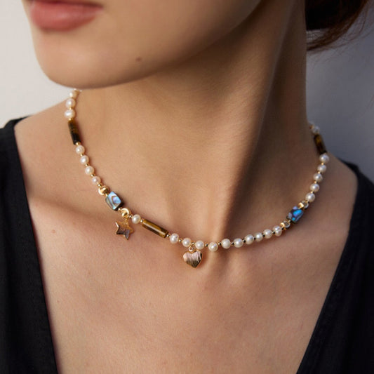Close-up of woman wearing pearl necklace with gold star and heart charms