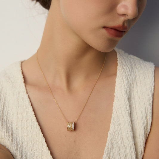 Close-up of woman wearing textured cream top and gold pendant necklace with diamond accents