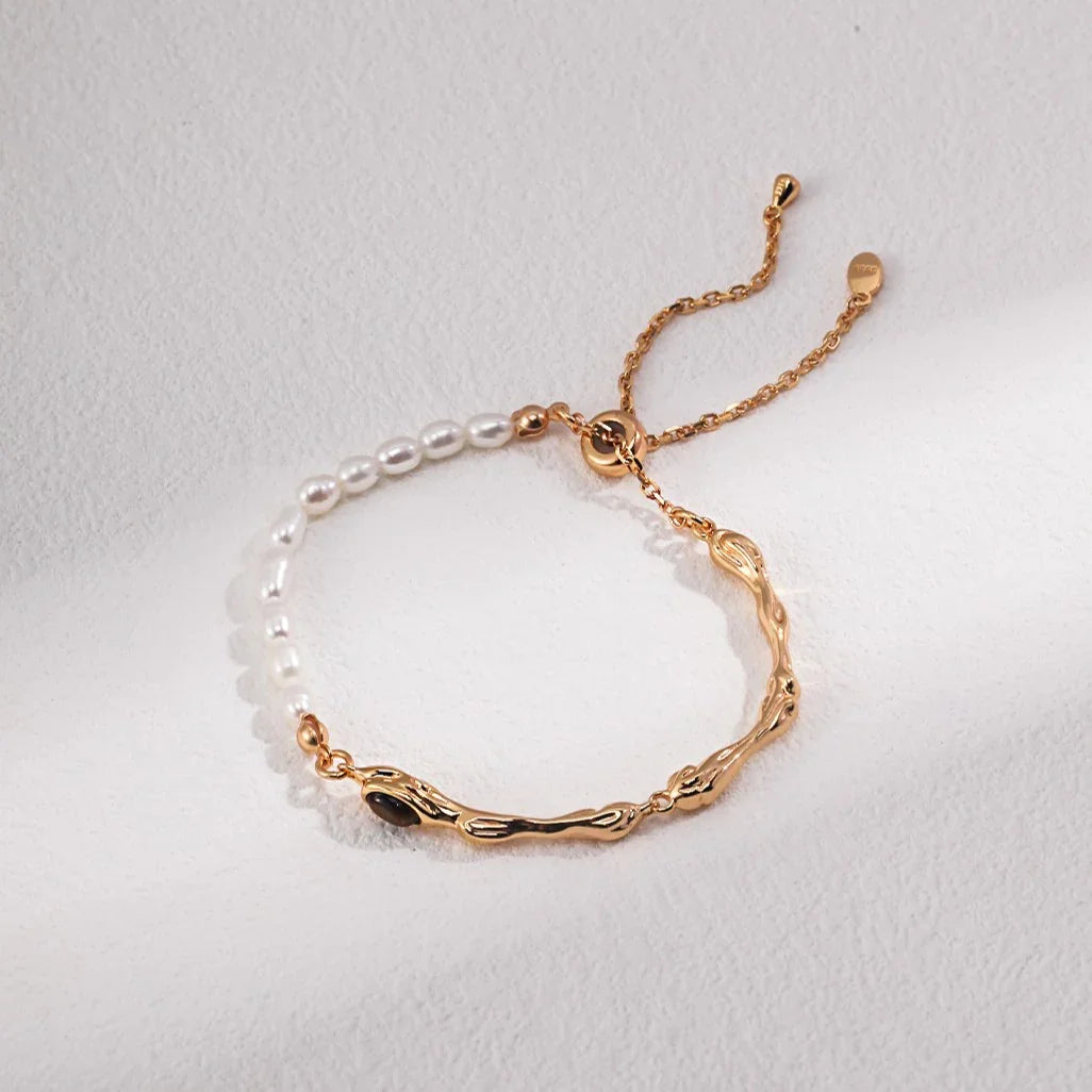 Elegant bracelet with white pearls and gold textured chain on a white textured surface